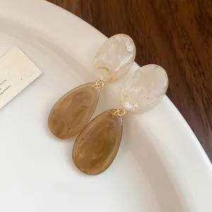 Gros plan sur d'élégantes boucles d'oreilles en résine ambre et crème effet marbre