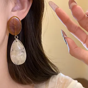 Vue détaillée de boucles d'oreilles en résine marbrée sur l'oreille du mannequin