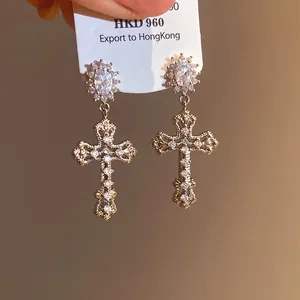 Macro view showing the intricate cubic zirconia inlay on the 18k gold cross earring.