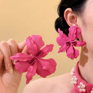 Close-up of oversized magenta flower stud earrings on model for vacation beach style