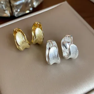 Macro detail of 18K gold-plated brushed texture round ear cuffs in gold and silver.