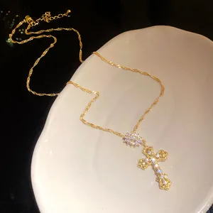 Detail of sparkling 18k gold plated cross pendant necklace with zircon stones.