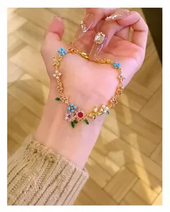 Handheld close-up of a luxury gold-plated bracelet with zircon and pearl flower charms