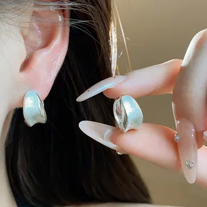 Close-up of 18K gold plated brushed silver earrings showing elegant curved texture