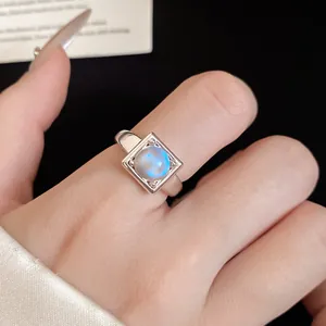 Close-up of minimalist square open ring with glowing iridescent moonstone.