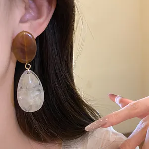 Vue détaillée de boucles d'oreilles pendantes en résine marbrée élégante avec tige en argent