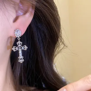 Detailed view of an elegant 18k plated zirconia cross pendant earring worn by model