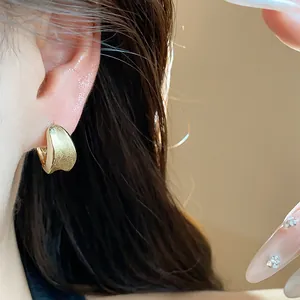 Macro detail shot showing the brushed texture of a minimalist gold plated ear buckle