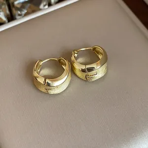 Detail of 18K gold plated hoop earrings featuring a sophisticated brushed matte texture.