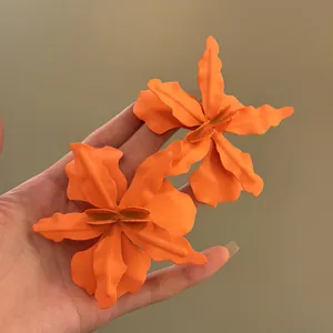 Close-up showing the matte texture of large orange petal flower stud earrings set