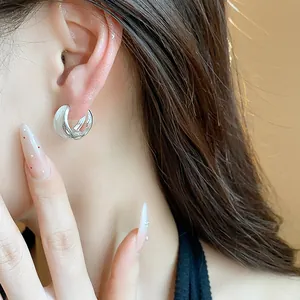 Close-up of elegant brushed and polished silver interlocking hoop earrings on model