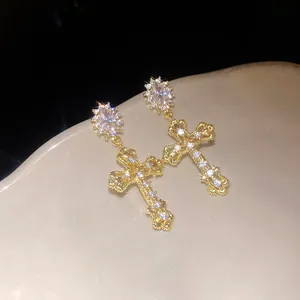 Close-up of 18k gold plated cross earrings with sparkly cubic zirconia stones.