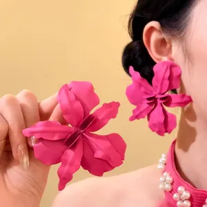 Macro view of oversized hot pink flower earrings on model for a vacation style