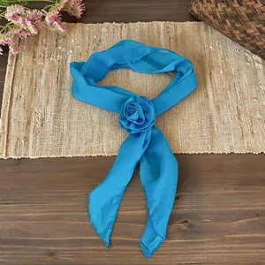 Detailed view of an elegant blue chiffon scarf accessory featuring a delicate fabric rose