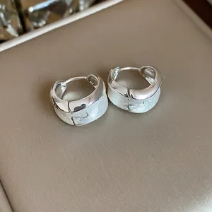 Close-up of minimalist brushed silver hoop earrings with elegant textured finish.