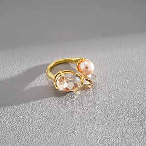 Detailed view of luxury gold open ring with faux pearl and oval faceted crystal