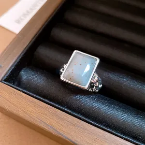 Close-up of a square stone ring with a blue gemstone in a black velvet display box.