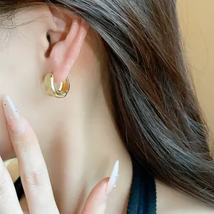 Close-up of 18K gold-plated brushed minimalist hoop earrings worn on ear