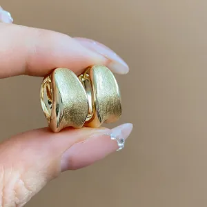 Detailed macro view showing the elegant brushed texture of 18K gold plated hoop earrings.