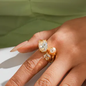 Exquisite gold-tone open ring featuring a large oval crystal, faux pearl, and square rhinestone