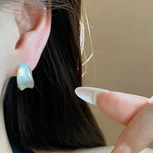 Detail shot of a minimalist brushed silver hoop earring worn on an ear for elegant style