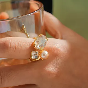 Elegant gold open ring featuring oval and square crystals with a pinkish faux pearl detail