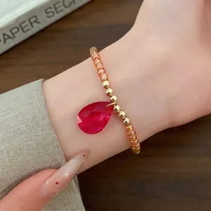 Bracciale vintage di perline di vetro con pendente a goccia rosso indossato al polso