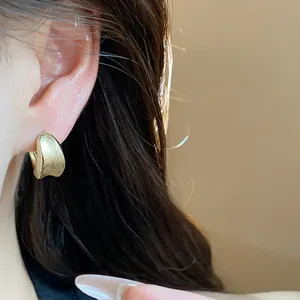 Close-up detail of a minimalist 18K gold plated hoop earring with elegant brushed texture