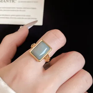 Detailed view of a minimalist 18k gold plated open ring with a square blue stone on finger