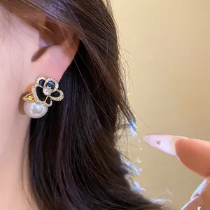 Detail view of 14k gold plated flower stud earring with zircon and white pearl on ear