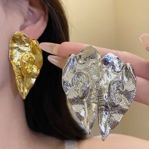 Détail de boucles d'oreilles vintage en forme de feuille avec une finition en métal froissé.