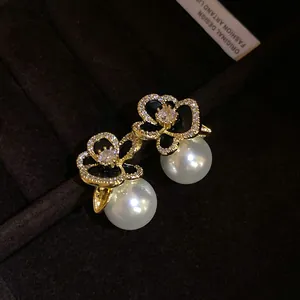 Detailed view of 14k gold-plated zircon flower earrings with elegant white pearls