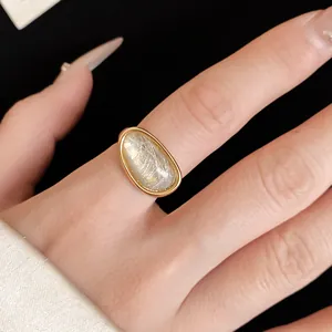Detailed view of an 18k gold plated open ring with an elegant oval rutilated stone