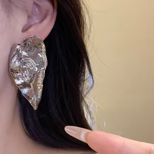 Gros plan de boucles d'oreilles feuilles métalliques vintage avec texture plissée
