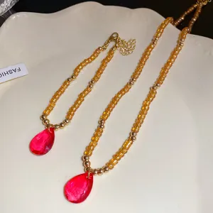 Primo piano di una collana vintage in perle di vetro con ciondolo a goccia rosso