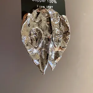 Détail de boucles d'oreilles vintage en métal argenté avec relief en forme d'oreille