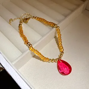 Dettaglio ravvicinato di una collana vintage di perline con un pendente a goccia rosso sfaccettato