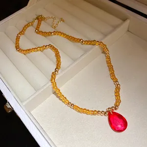 Elegante collana vintage di perline con ciondolo a goccia rosso in un portagioie raffinato.