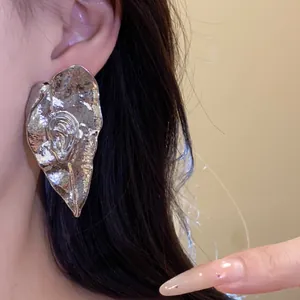 Gros plan de boucles d'oreilles vintage en métal plissé en forme de feuille d'argent