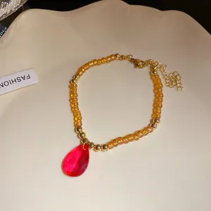Dettaglio della collana vintage in perle di vetro ambrato con ciondolo a goccia rosso