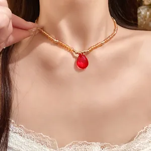 Elegante collana vintage con pendente a goccia in vetro rosso e perline dorate.