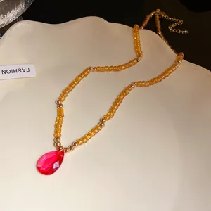 Collana di perle vintage ambra con un ciondolo a goccia in vetro rosso brillante.