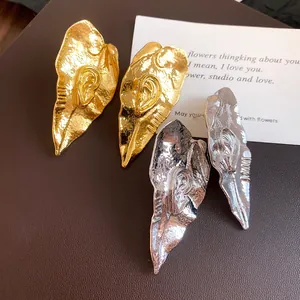 Vue détaillée de boucles d'oreilles feuilles métalliques vintage en or et argent