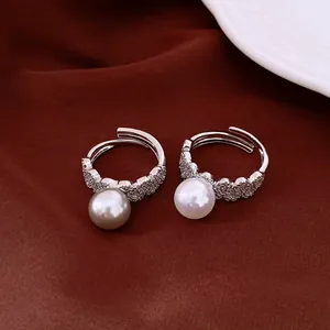 Close-up detail of vintage lace-textured pearl rings with pavé stones on dark red fabric