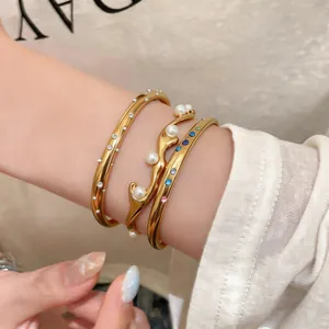 Detailansicht goldener Edelstahlarmreifen mit Perlen und bunten Kristallen in Lagenoptik.
