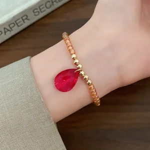 Dettaglio di un bracciale di perline vintage con ciondolo a goccia in cristallo rosso
