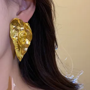 Gros plan détaillé montrant la texture froissée unique des boucles d'oreilles vintage dorées