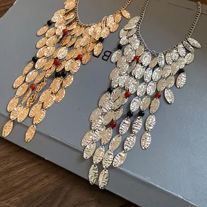Detail view of gold and silver hammered oval leaf necklaces with agate bead accents