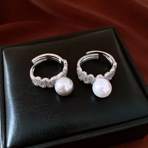 Close-up of elegant silver lace pearl rings with micro-set diamonds on jewelry box