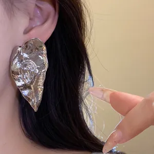 Détail d'une boucle d'oreille en métal argenté en forme de feuille plissée de style vintage